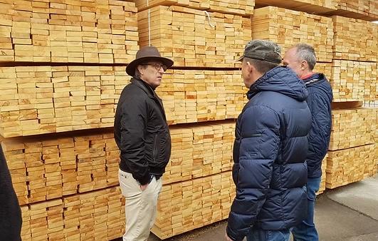Jef Deturck com representantes de uma serraria diante de madeira empilhada na Ucrânia
